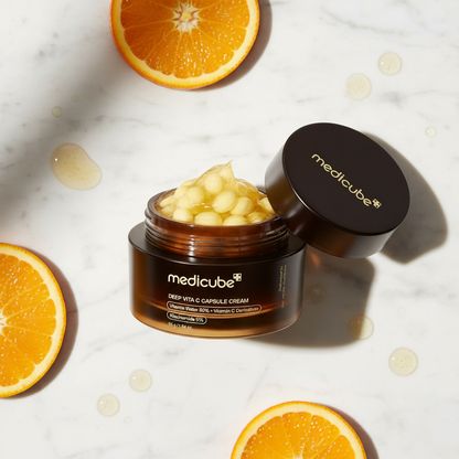 Medicube Deep Vita C Capsule Cream with orange slices on marble surface