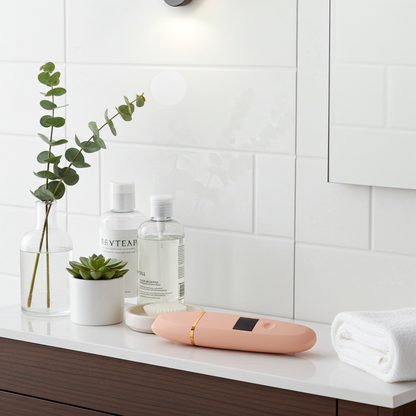 Ultrasonic Skin Scrubber white on white marble with facial serum, jade roller and white orchid – ultrasonic spatula for deep pore cleansing and skin lifting